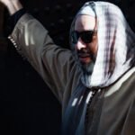 A man wearing sunglasses and a traditional Moroccan outfit stands outdoors in Rabat, Morocco.