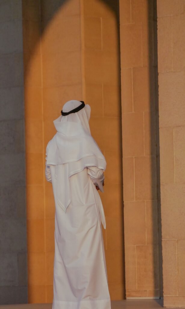 A man in traditional Bahraini clothing standing thoughtfully, showcasing Middle Eastern culture.
