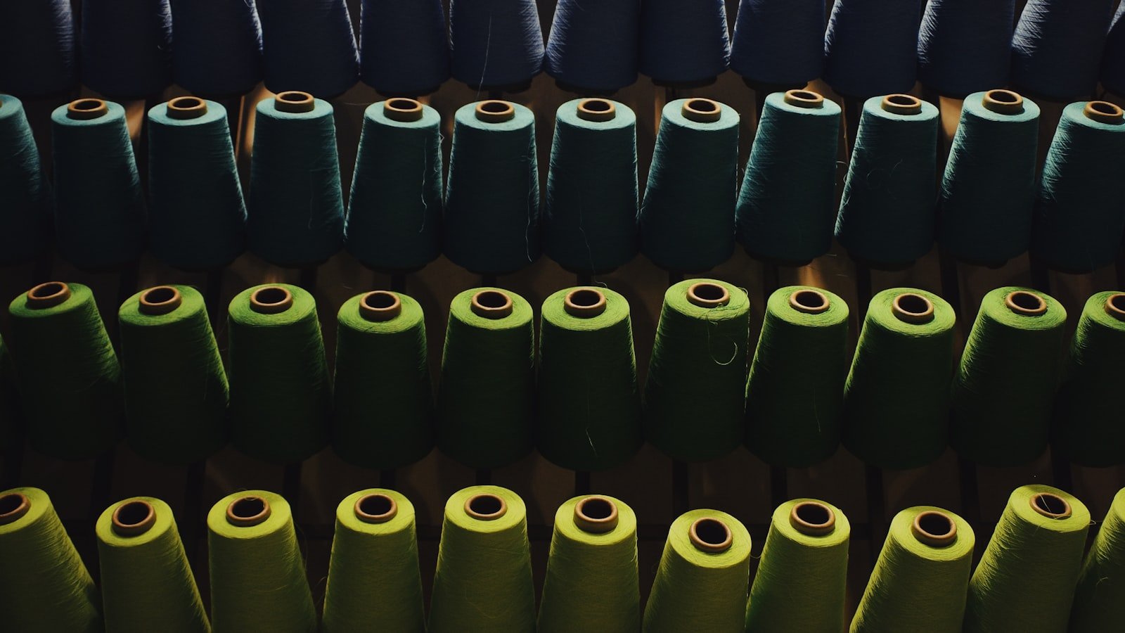 Spools of yarn in a textile workshop where thobe fabric is woven and finished