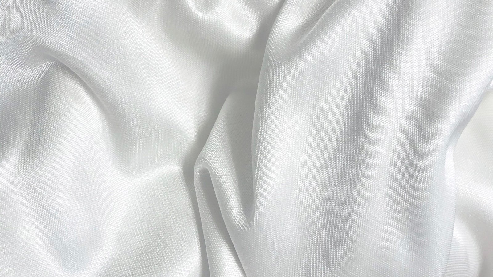 White thobe fabric laid flat on a tailor's cutting table