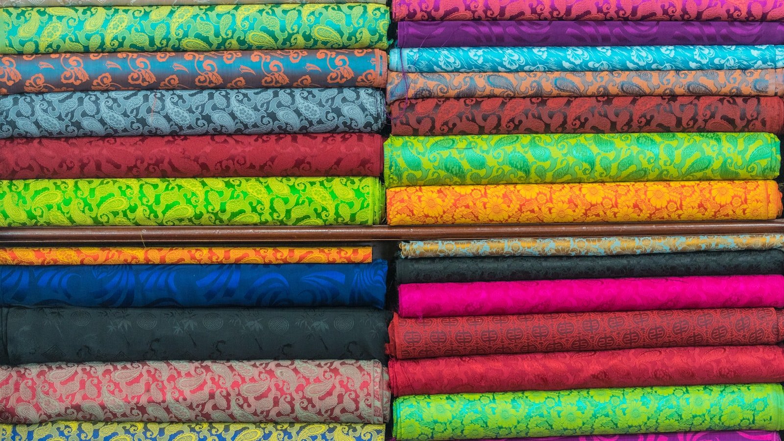 Assorted textile fabrics stacked together, representing the multiple thobe fabric constructions available for wholesale supply