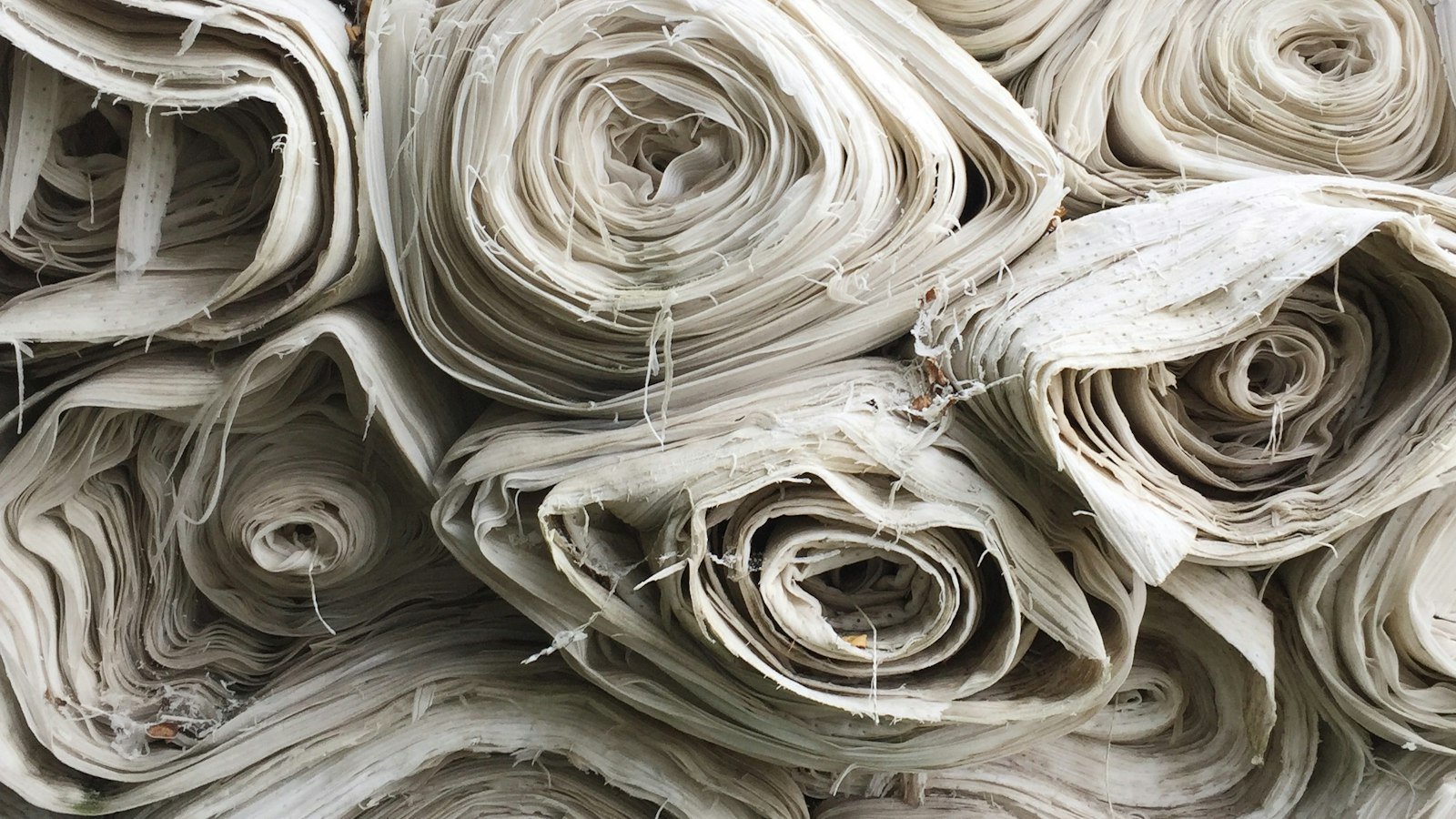 White textile lot, representing the plain white cotton, TC and polyester fabric options a UAE kandura maker can compare before ordering in bulk