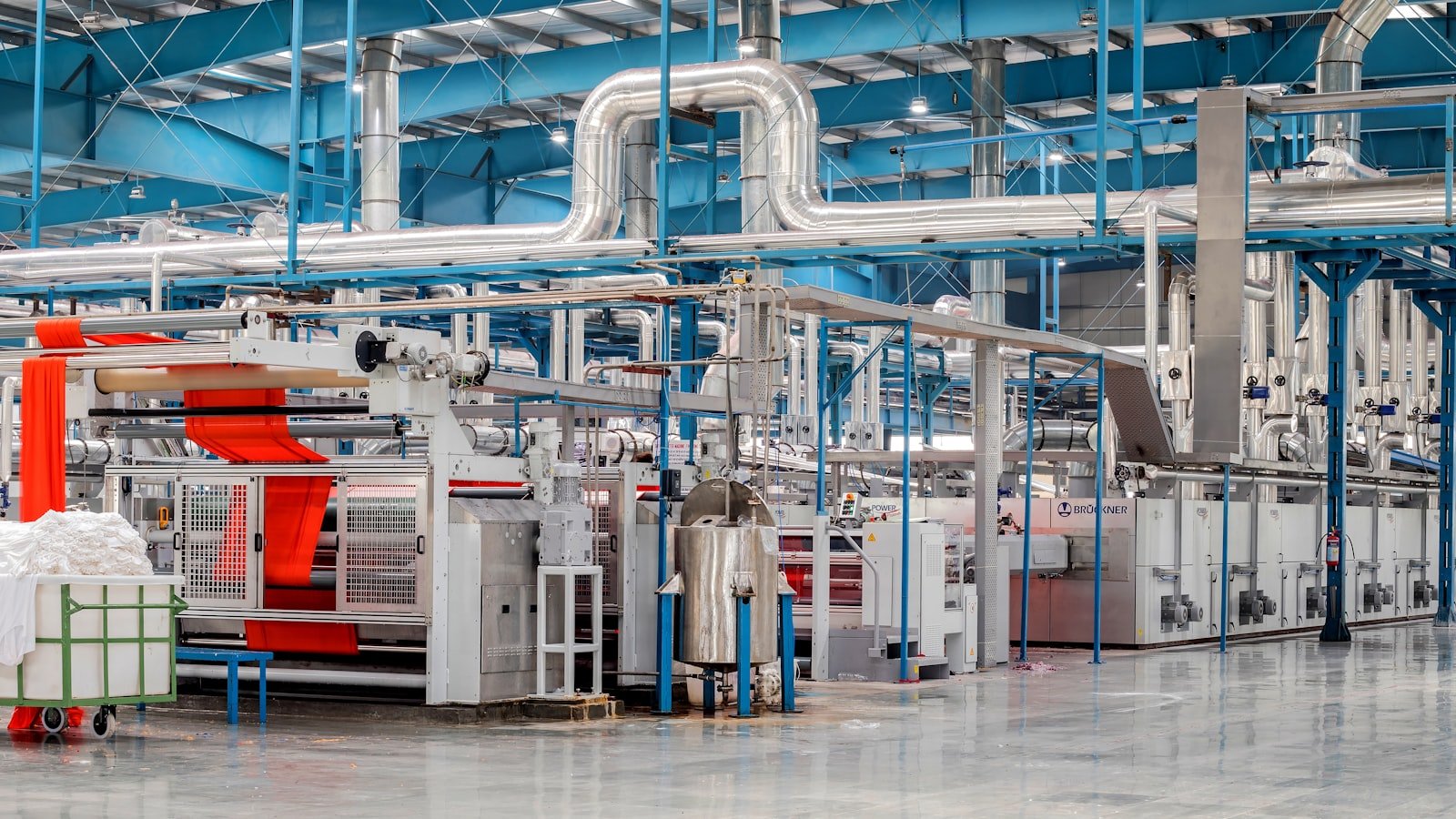 A large industrial textile factory floor with rows of machinery, showing the production scale behind a consistent thobe fabric supply