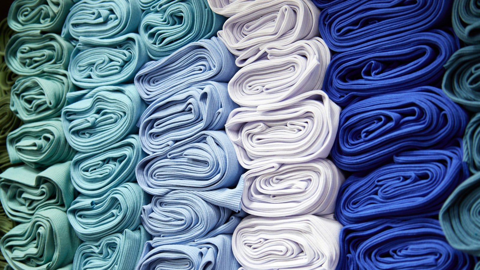 Neatly folded white fabric stacks in a factory warehouse, the first visual check a UAE kandura maker runs before bulk ordering
