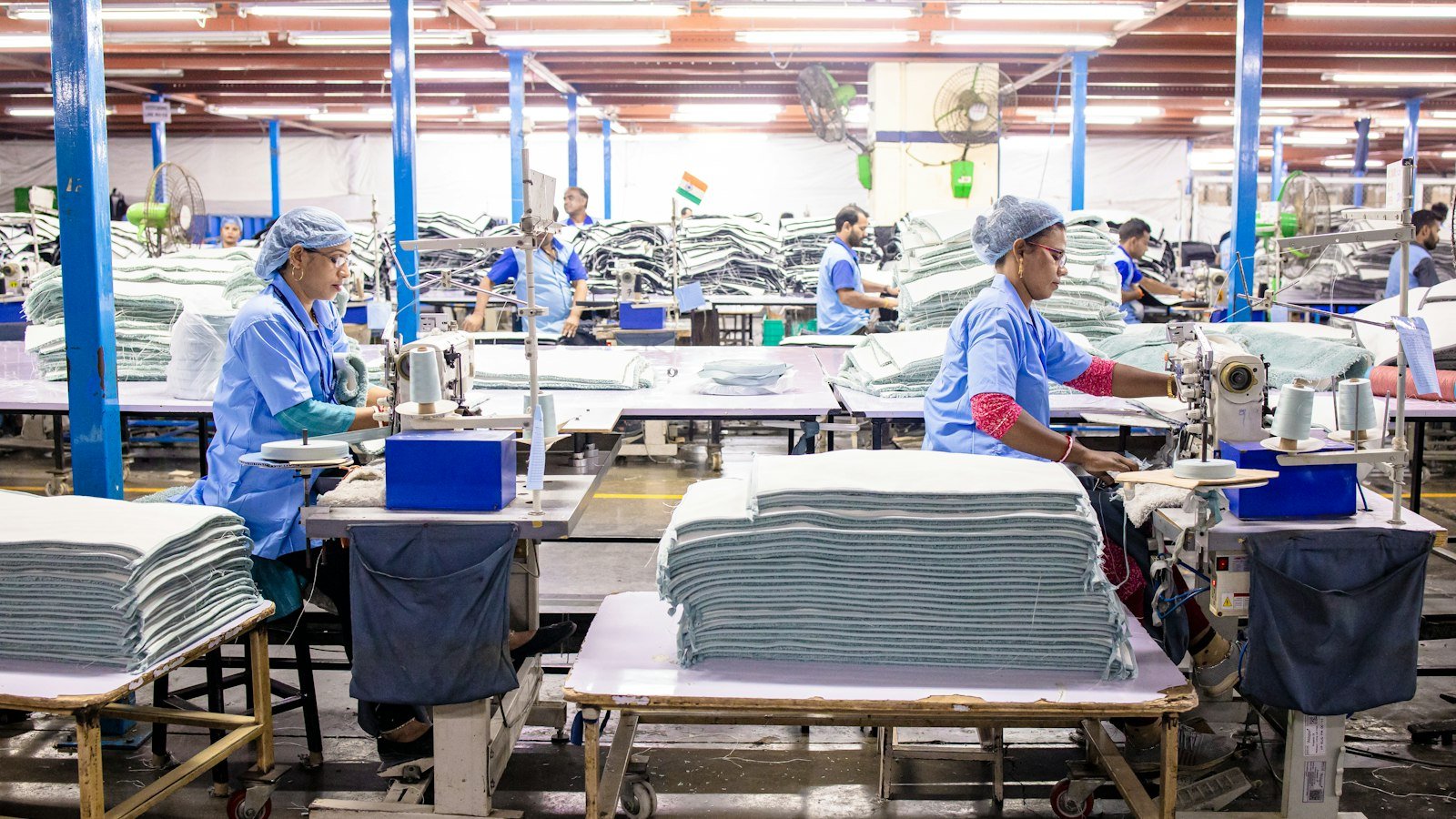 Workers sewing fabric on an industrial line, the garment factory stage where thobe fabric becomes a finished thobe